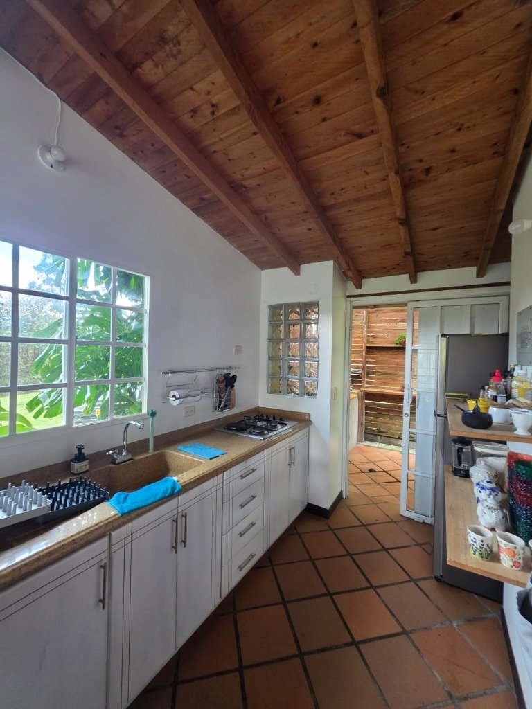 Cocina integral campestre amoblada y equipada con estufa de gas, mesón y estanterías en Casa Campestre La Isabela