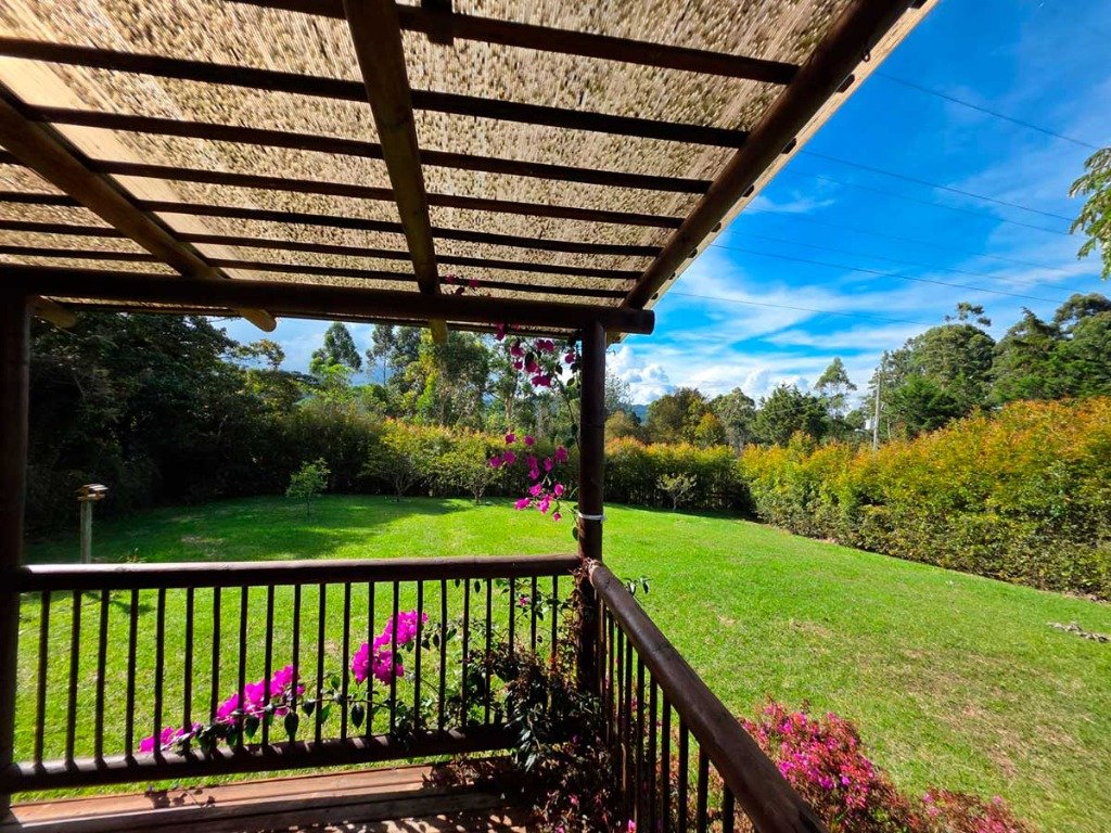 Vista panorámica al jardín, flores veraneras y montañas desde el pórtico de madera en Casa Campestre La Isabela La Ceja